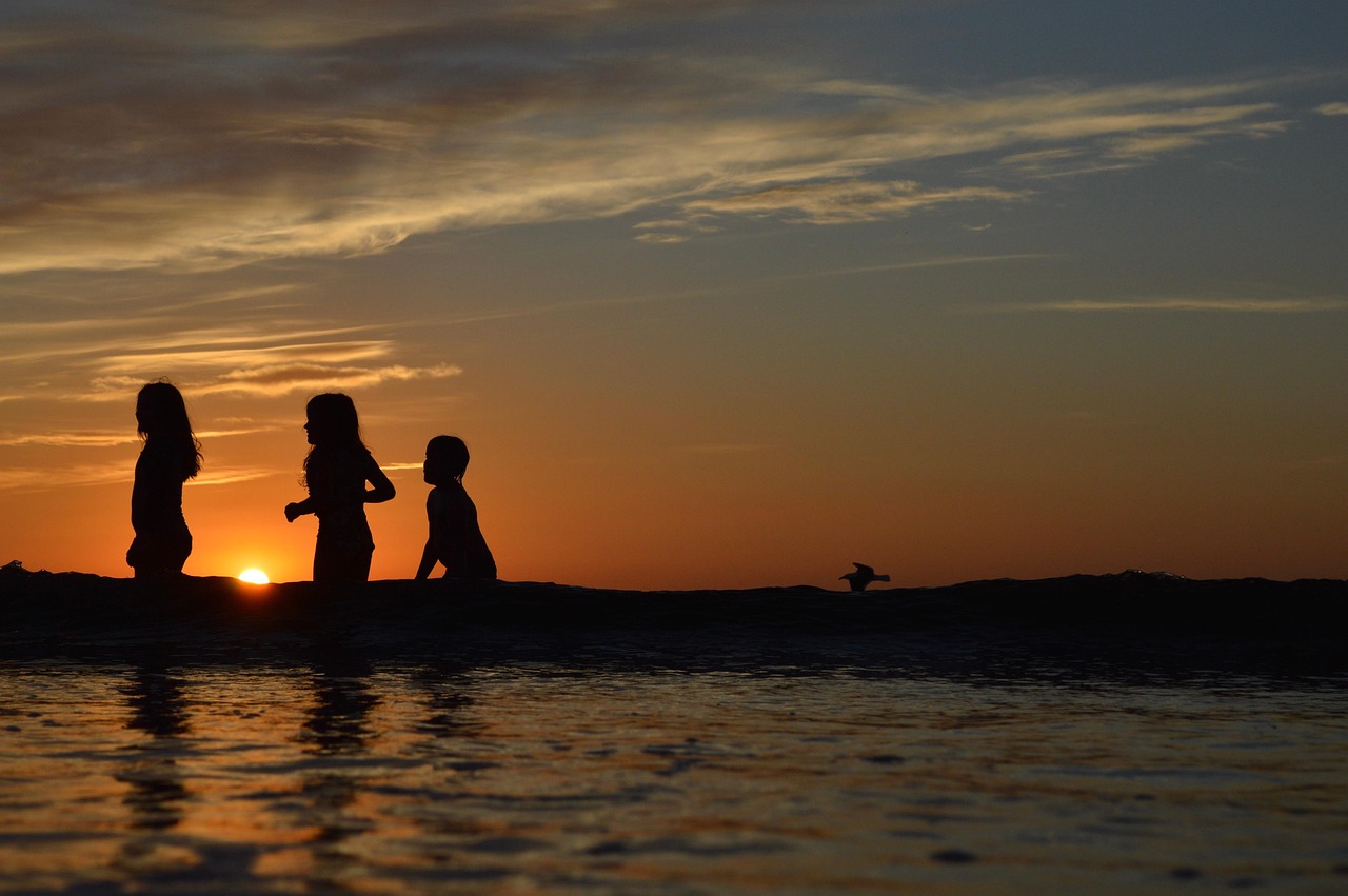 Enfants jouant au bord de l eau sur une plage au coucher du soleil